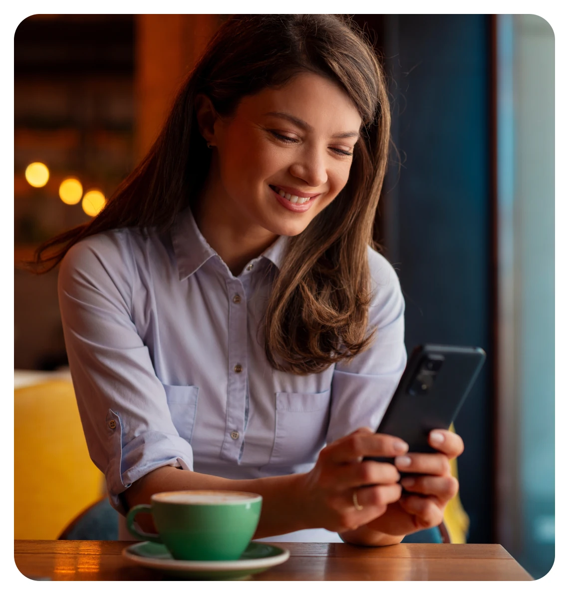 Smiling woman reading her phone over a cup of coffee