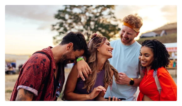 Four smiling friends looking at a phone together