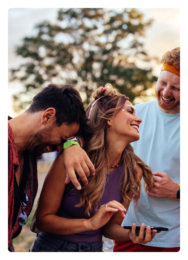 Three smiling friends laughing over a phone
