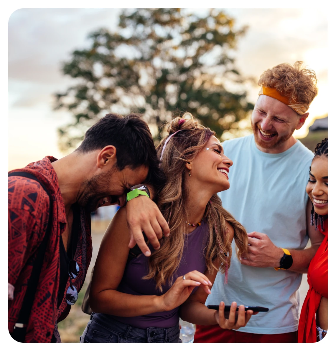 Four smiling friends looking at a phone together