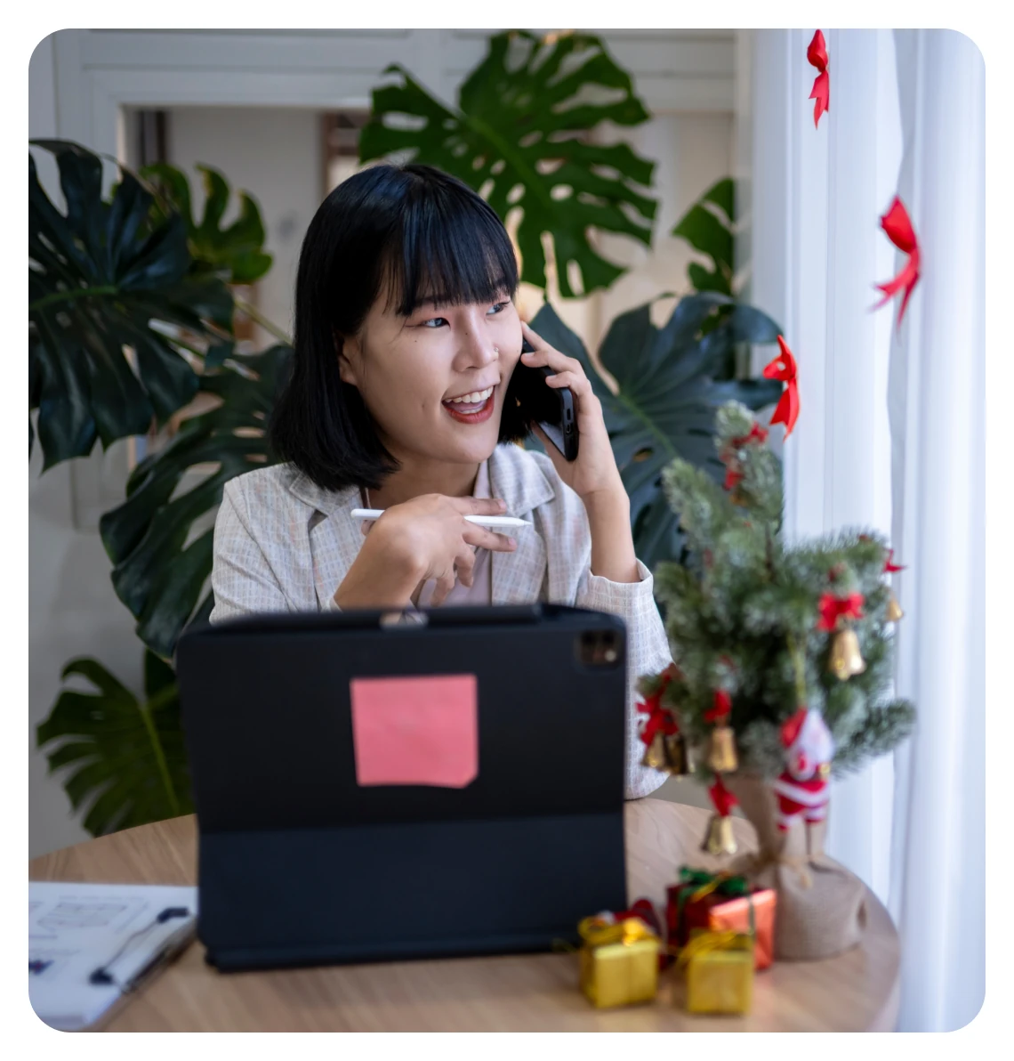 Woman on the phone beside her laptop and a Christmas tree