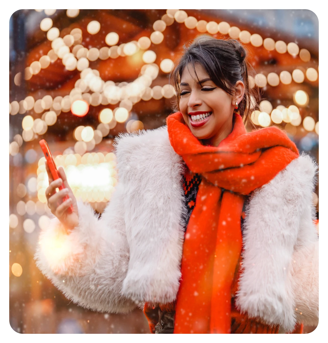 Smiling woman in a winter coat and an orange scarf among holiday lights